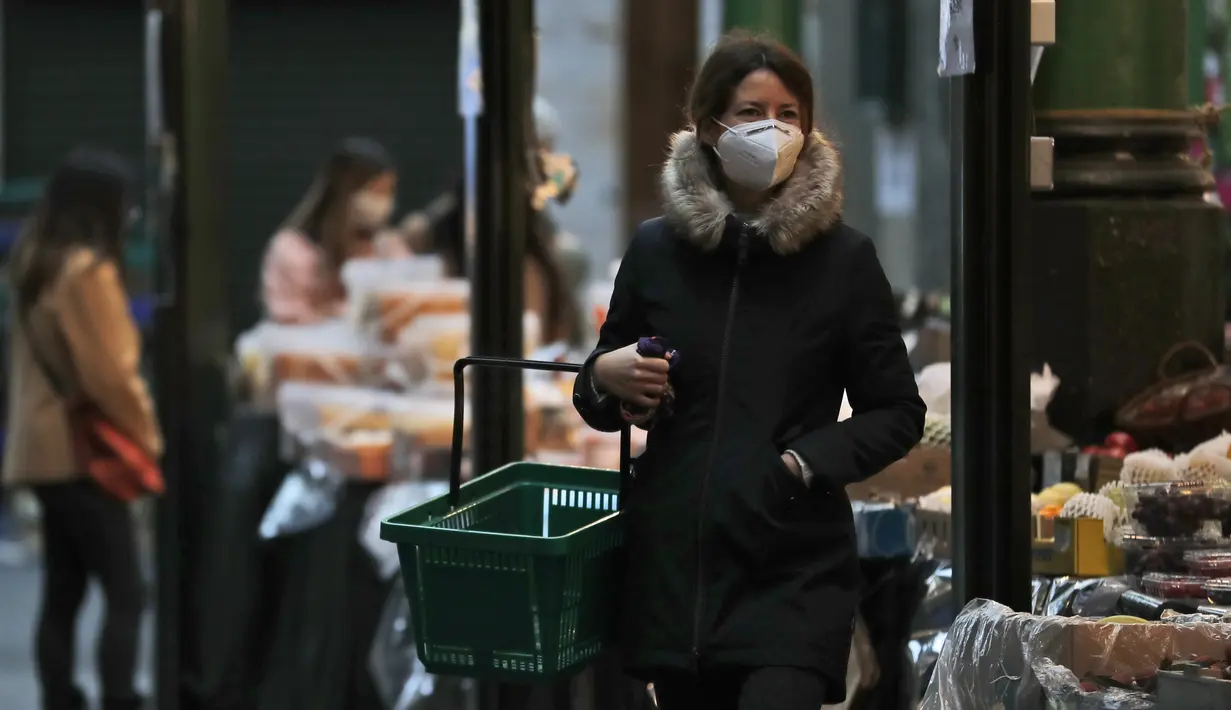 Seorang perempuan mengenakan masker saat berbelanja di Borough Market di London selatan selama penguncian nasional (lockdown) ketiga Inggris, Selasa (12/1/2021). Borough Market menjadi tempat pertama yang mewajibkan pemakaian masker di luar ruangan. (AP Photo/Alastair Grant)