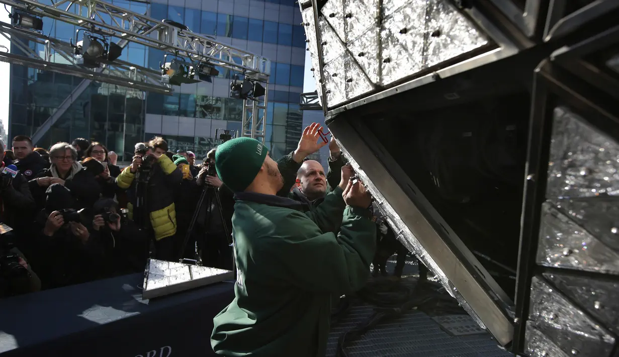 Pekerja memasang kristal berbentuk segitiga pada bola raksasa di atas sebuah gedung di Times Square, New York, Kamis (27/12). Menyaksikan bola kristal raksasa adalah tradisi yang tidak terlewatkan setiap perayaan tahun baru sejak 1904. (AP/Seth Wenig)