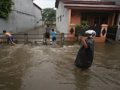 Warga melintasi banjir yang menggenangi Jalan Ketapang di kawasan Pasar Minggu, Jakarta, Selasa (4/10). Banjir yang berasal dari luapan Kali Anur tersebut menyebabkan Jalan Ketapang tidak bisa dilewati kendaraan. (Liputan6.com/Immanuel Antonius)
