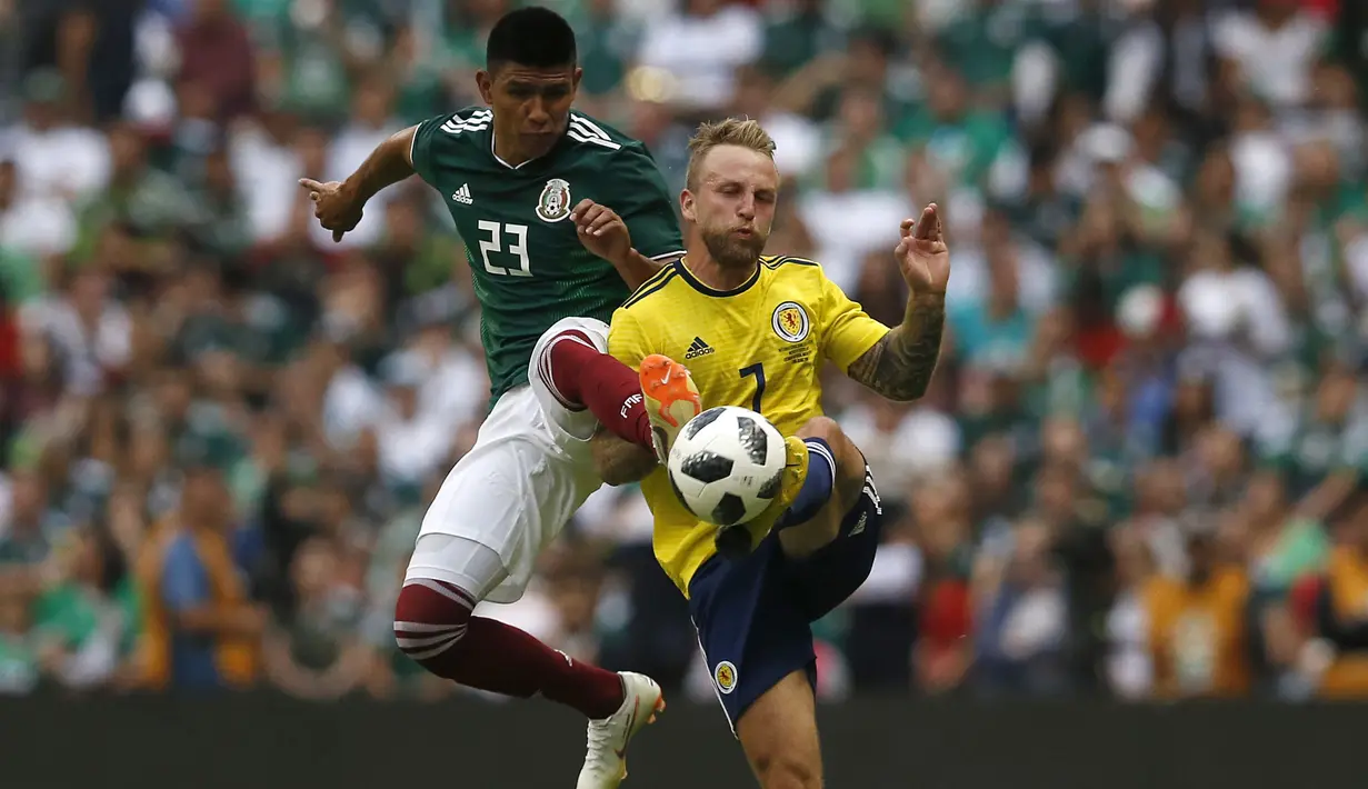 Aksi pemain Meksiko, Jesus Gallardo (kiri) berebut bola dengan pemain Skotlandia, Johnny Russell pada laga uji coba di Azteca Stadium, Meksiko City, (2/6/2018). Meksiko menang 1-0. (AP/Rebecca Blackwell)