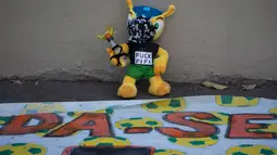 Sebuah boneka Fuleco Armadillo (maskot resmi Piala Dunia 2014) dihias menyerupai demonstran yang melakukan aksi unjuk rasa di Rio de Janeiro, Brasil, (15/6/2014). (REUTERS/Marco Bello)