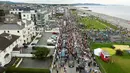 Para penggemar penyanyi Sinead O'Connor berbaris di jalan saat iring-iringan pemakamannya melewati bekas kampung halamannya di Bray, Co Wicklow, Irlandia, Selasa (8/8/2023). Sekitar 3.000 lebih orang memadati jalan sepanjang rute tepi laut di Bray. (Niall Carson/PA via AP)
