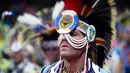 Seorang pria mengenakan kostum dan atribut kepala bersiap mengikuti Grand Entry of the Denver March Powwow di Denver, Colorado (24/3). (AFP/Jason Connolly)