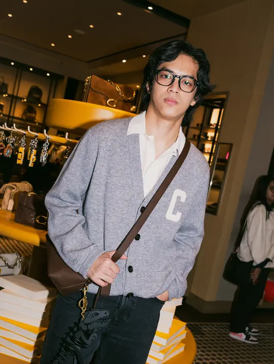 Tak hanya perempuan, para selebriti pria juga tampil tak kalah stylish. El Putra Sarira mengusung gaya smart casual lewat cardigan abu-abu dengan aksen huruf “C”, dipadukan dengan celana hitam dan sling bag kulit cokelat. Look ini terasa clean, modern, dan wearable, mewakili estetika urban yang timeless.  [Dok/KANMO GROUP].
