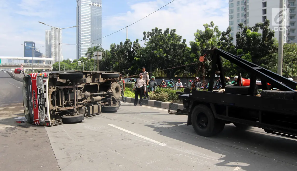 Mobil derek menarik mobil boks yang terguling Jalan Casablanca, Jakarta, Rabu (27/6). Mobil bernomor polisi B 9515 FCC terguling setelah menabrak pembatas jalan. (Liputan6.com/Arya Manggala)