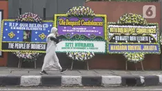 Pejalan kaki melintas dekat karangan bunga duka cita atas meninggalnya Ratu Elizabeth II di depan Kedutaan Besar (Kedubes) Inggris, kawasan Kuningan, Jakarta, Jumat (9/9/2022). Ratu Elizabeth II memerintah Inggris Raya dan 14 wilayah Persemakmuran lainnya, dan menjadi salah satu wanita paling terkenal dalam sejarah. (Liputan6.com/Herman Zakharia)