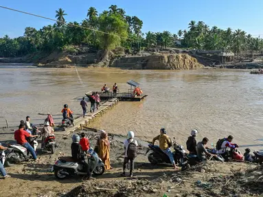 Sejumlah warga menunggu waktu naik rakit tali untuk menyeberangi Sungai Peusangan menyusul banjir bandang yang menghancurkan desa-desa di sekitarnya di Kabupaten Bireuen, provinsi Aceh, pada Senin 5 Januari 2026. Sebulan lebih pasca terjangan banjir bandang, warga di sekitar Sungai Peusangan Bireuen Aceh masih menggunakan metode penyeberangan darurat. (CHAIDEER MAHYUDDIN/AFP)