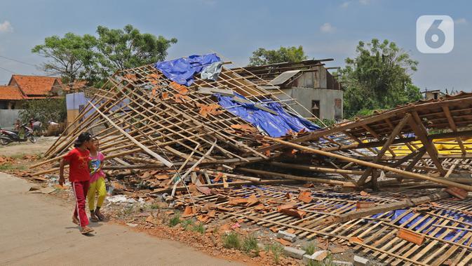 DAMPAK PUTING BELIUNG DI BEKASI: Anak-anak melintasi puing-puing bangunan rumah yang rusak diterjang angin puting beliung di Kaliabang Tengah, Kota Bekasi, Sabtu (24/10/2020). Sebanyak 159 rumah terdampak puting beliung yang terjadi Jumat siang. (Liputan6.com/Herman Zakharia)