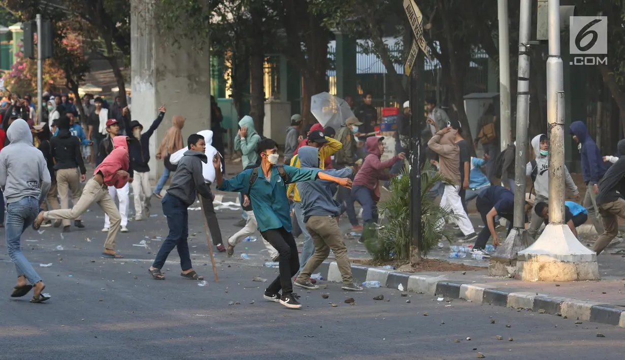 Massa melemparkan batu ke arah barisan polisi dalam unjuk rasa di sekitaran Gedung DPR RI, Jakarta, Senin (30/9/2019). Kericuhan pecah lantaran massa yang kebayakan terdiri dari pelajar tersebut berusaha masuk ke area depan DPR. (Liputan6.com/Angga Yuniar)