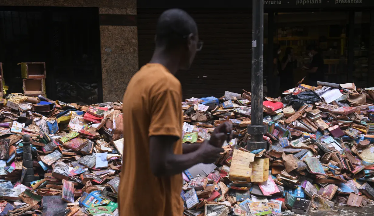 Ribuan buku rusak terlihat di jalan setelah hujan lebat membanjiri toko buku di Petropolis, Brasil, 19 Februari 2022. Sebanyak 136 jenazah telah diidentifikasi hingga kini, menurut pejabat pertahanan sipil, di kota wisata yang biasanya indah, sekitar 60 km utara Rio de Janeiro. (MAURO PIMENTEL/AFP)