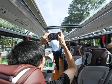 Seorang pria mengambil foto di dalam sebuah bus wisata di Shenzhen, Provinsi Guangdong, China selatan (22/10/2020). Shenzhen pada Kamis (22/10) meluncurkan tiga jalur bus wisata bagi wisatawan, yang masing-masing menampilkan budaya, teknologi, dan pemandangan malam kota tersebut. (Xinhua/Mao Siqian)