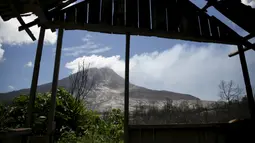 Gunung Sinabung terlihat dari puing rumah yang rusak akibat erupsi di Beras Tepu Desa, Karo, Sumatera Utara, 21 Juni 2015. Ribuan warga yang tinggal di sekitar lereng Gunung Sinabung meninggalkan rumah mereka. (REUTERS/Beawiharta)