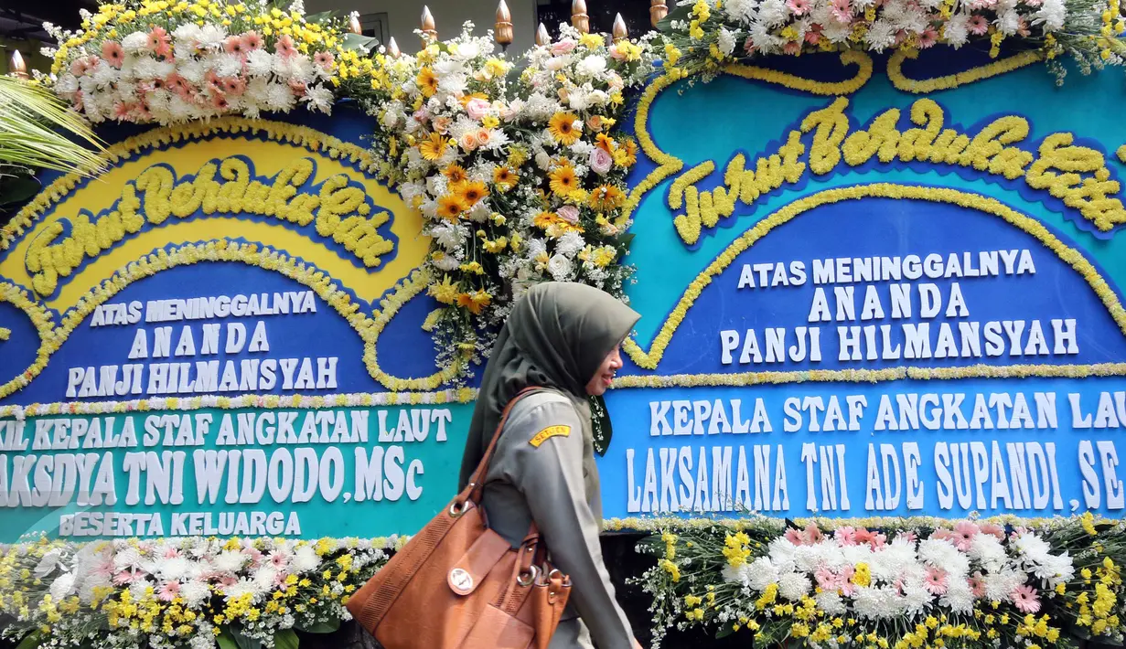 Seorang warga berjalan di deretan karangan bunga ucapan bela sungkawa atas meninggalnya putra Menteri Susi, almarhum Panji Hilmansyah di luar kediaman Menteri Kelautan dan Perikanan tersebut, Jakarta, Senin (18/1/2016). (Liputan6.com/Helmi Afandi)