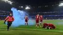 Seorang petugas mengambil flare saat pemain Liverpool Mohamed Salah bersama rekannya Sadio Mane melakukan selebrasi dalam pertandingan Liga Champions di Etihad Stadium (10/4). Salah menyumbang satu gol untuk Liverpool. (AFP/Paul Ellis)