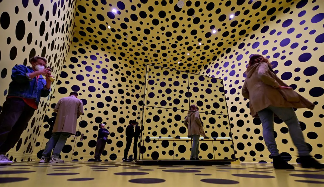 Pengunjung berjalan melewati ruang instalasi seni berjudul 'The spirit of the pumpkins descended into the heavens' (2015) karya seniman kontemporer Jepang Yayoi Kusama dalam pameran Yayoi Kusama: A Retrospective di Atrium Martin Gropius Bau, Berlin, Jerman, Selasa (19/5/2021). (John MACDOUGALL/AFP)