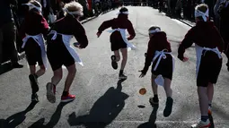 Peserta menjatuhkan pancake saat lomba lari sembari membawa wajan berisi pancake di Olney, Buckinghamshire, Inggris, Selasa (28/2). Lomba yang digelar pada Hari Pancake atau Pancake Day ini diadakan satu hari menjelang Rabu Abu. (AP Photo/Alastair Grant)