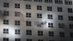 Orang-orang menyalakan lampu dari jendela di hotel-kasino Grand Diamond City saat api membakar gedung di Poipet pada 29 Desember 2022. Sebanyak 10 orang tewas dalam kebakaran di kasino-hotel Kamboja di perbatasan Thailand , dengan foto-foto yang menunjukkan kelompok-kelompok berkerumun mati-matian di tepian saat api yang ganas mengelilingi mereka. (AFP/STR)