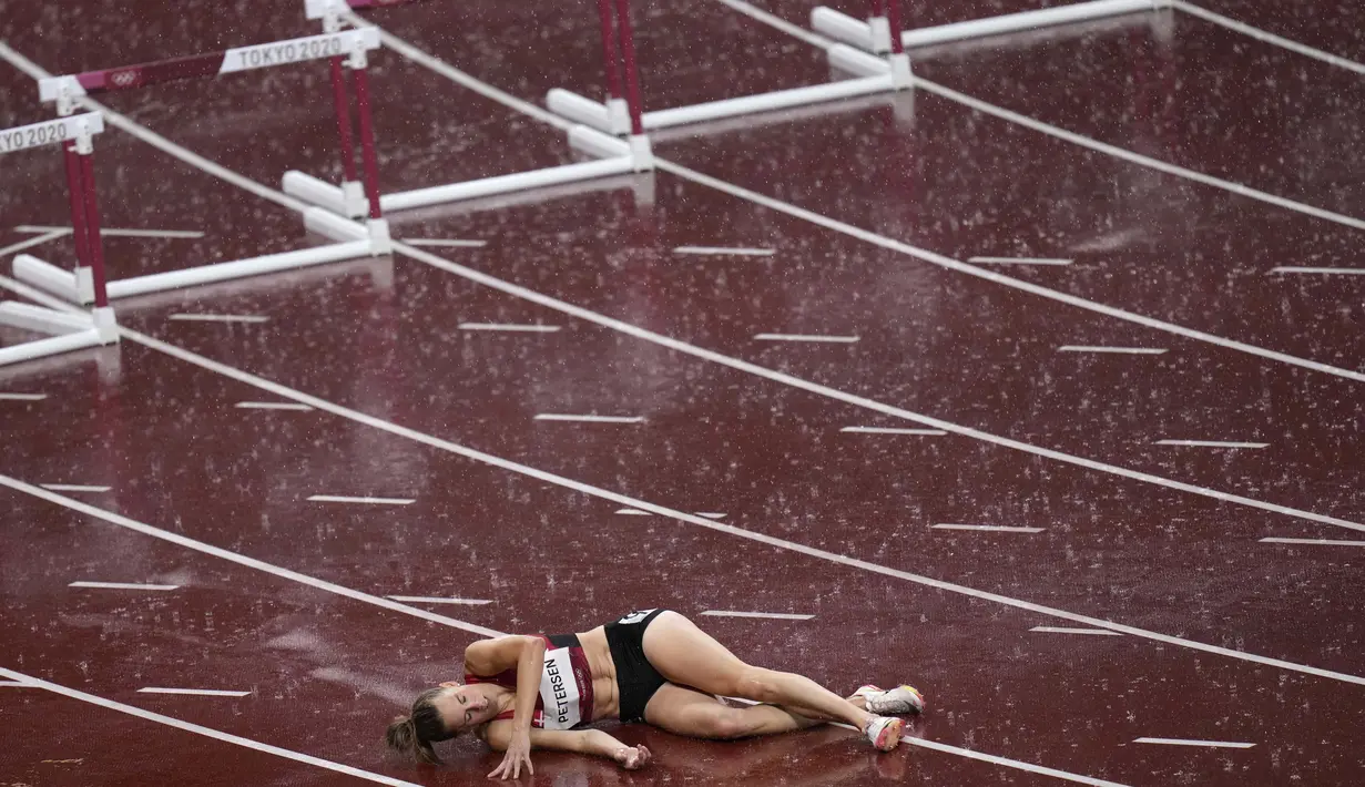 Sara Petersen, dari Denmark, terbaring di lintasan setelah terjatuh saat pertandingan semifinal lari gawang 400 meter putri pada Olimpiade Tokyo 2020,  Senin (2/8/2021). (Foto: AP/Francisco Seco)