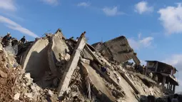 Warga Suriah berkumpul di atas reruntuhan bangunan yang runtuh di kota Jandaris, bagian provinsi Aleppo saat operasi pencarian korban gempa bumi, Selasa (7/2/2023). Berdasar informasi pemerintah setempat dan tim penyelamat, sedikitnya 1.444 orang tewas di seluruh Suriah setelah gempa bumi dahsyat yang berpusat di barat daya Turki. (Mohammed AL-RIFAI/AFP)