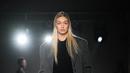Gigi Hadid berjalan di catwalk saatmempersembahkan kreasi Prada selama Koleksi Wanita Musim Gugur-Musim Dingin 2023-2024 sebagai bagian dari Fashion Week di Milan pada 23 Februari 2023. Model asal AS itu tampil sangat stylish dalam balutan jas panjang abu-abu berlapis di atas jumper hitam dan mengenakan sepasang celana pendek abu-abu panjang yang unik, dihiasi dengan bunga putih tiga dimensi yang halus. (AFP/Marco Bertorello)
