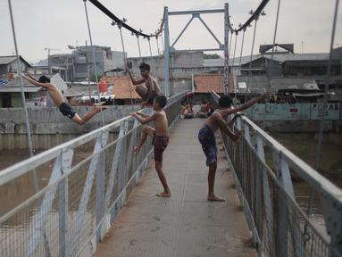 Seorang anak melompat dari atas jembatan dan berenang di aliran kali besar Banjir Kanal Barat, Jakarta, Sabtu (11/3). Minimnya pengawasan orang tua membuat mereka bermain di tempat berbahaya dan mengancam keselamatan. (Liputan6.com/Faizal Fanani)