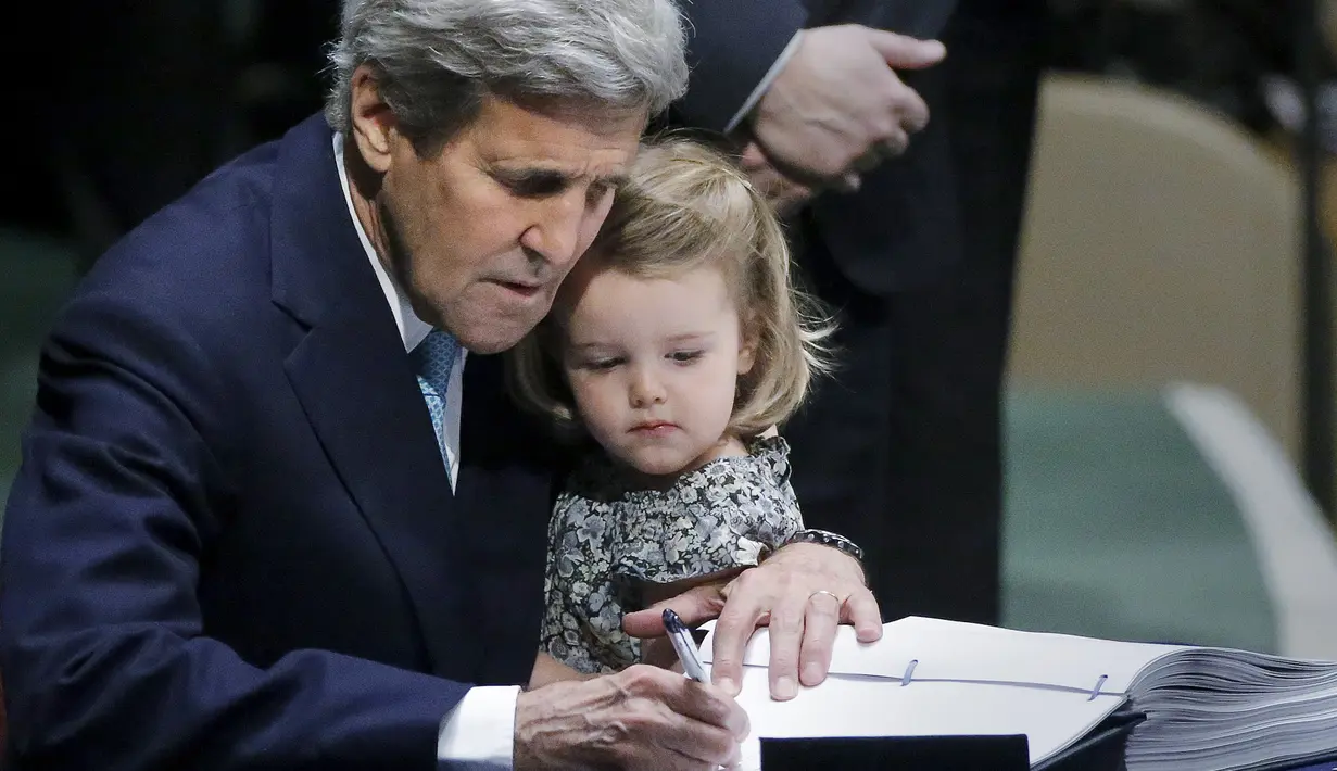 Menteri Luar Negeri AS John Kerry menggendong cucunya Isabelle Dobbs-Higginson saat menandatangani surat Perjanjian Paris tentang perubahan iklim di Markas Besar PBB, Manhattan, New York, AS (22/4). (REUTERS / Carlo Allegri)