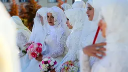 Mempelai perempuan menunggu prosesi pernikahan pada perayaan Rusia City Day di Grozny, Rusia, (5/10). Sebanyak 199 pasangan menikah di Taman Bunga Grozny pada perayaan tersebut. (AP Photo / Musa Sadulayev)