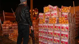 Seorang petugas bea cukai bersenjata memeriksa kotak jeruk palsu berisi pil Captagon di Pelabuhan Beirut, Lebanon, 29 Desember 2021. Bea Cukai Lebanon menyita sembilan juta pil Captagon dalam jeruk palsu yang ditujukan ke salah satu negara Teluk. (ANWAR AMRO/AFP)