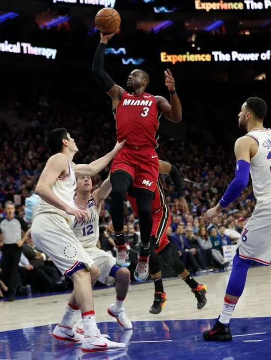 Pemain Miami Heat, Dwyane Wade melakukan tembakan melewati adangan para pemain Philadelphia 76ers pada NBA basketball playoff series di Wells Fargo Center, Philadelphia, (16/4/2018). Heat menang 113-103. (AP/Chris Szagola)