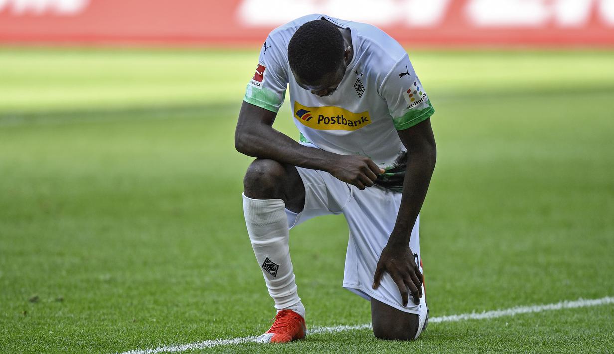 Pemain Borussia Moenchengladbach, Marcus Thuram, melakukan selebrasi berlutut untuk menghormati mendiang George Floyd pada laga Bundesliga di Stadion Borussia-Park, Minggu (31/5/2020). Moenchengladbach menang 4-1 atas Union Berlin. (AP/Martin Meissner)