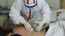 Seorang pasien yang terinfeksi virus corona COVID-19 menerima perawatan dengan teknik medis tradisional Tiongkok yang dikenal sebagai "bekam" di Rumah Sakit Palang Merah di Wuhan di provinsi Hubei China (11/3/2020). China melaporkan peningkatan kasus virus corona pada Maret 11. (AFP/STR)