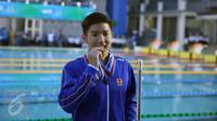 Perenang Jawa Barat, Ricky Anggawijaya menggigit medali emas usai berlomba kelas 200m gaya punggung putra di Gelanggang Renang FPOK UPI, Bandung, Senin (19/9/2016). Catatan waktu Ricky 2 menit 02,84 dtk. (Liputan6.com/Helmi Fithriansyah)