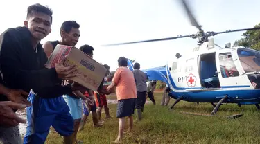 Warga gotong royong menurunkan barang dari helikopter PMI saat pendistribusian bantuan untuk korban banjir bandang dan longsor di Desa Cileuksa, Sukajaya, Bogor, Senin (6/1/2019). PMI mengerahkan helikopter lantaran lokasi bencana tidak bisa dijangkau melalui jalur darat. (Liputan6.com/Tim Media JK)