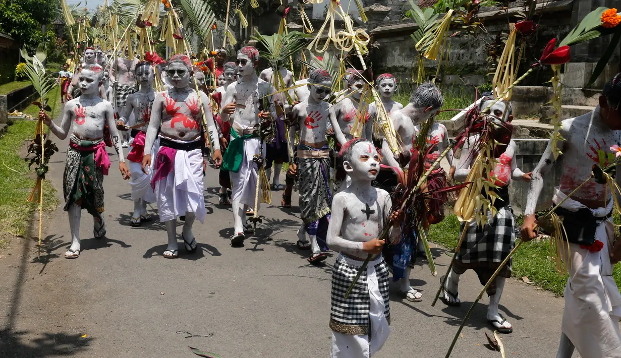 Para pemuda dengan cat tubuh berwarna-warni berkeliling kampung saat ritual Grebeg di Desa Tegallalang, Bali, Rabu (30/1). Tradisi ritual berkeliling kampung dengan riasan tubuh warna-warni itu dipercaya sebagai penangkal Roh jahat. (AP/Firdia Lisnawati)