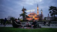 Orang-orang berbuka puasa selama bulan suci Ramadhan, di luar masjid Sultanahmet berlatar tulisan dalam bahasa Turki "Muhammad adalah utusan Allah", Istanbul, Turki, Rabu 25 Februari 2026. Sepanjang Ramadan, Masjid Sultanahmet di Istanbul, Turki, selalau ramai dikunjungi. (AP Photo/Emrah Gurel)