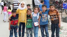 Anak-anak Suriah foto bersama di taman bermain sementara merayakan Idul Fitri, hari libur Muslim yang dimulai pada akhir bulan puasa Ramadhan, di Ariha di provinsi Idlib yang dikuasai pemberontak barat laut Suriah, (26/5/2020). (AFP Photo/Omar Haj Kadour)
