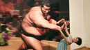 Seorang gadis berpose dengan gambar 3D pesumo pada pameran seni trik 3D karya seniman Jepang Masashi Hattori di Kawasaki, dekat Tokyo, Sabtu, (5/8). (AP Photo / Koji Sasahara)