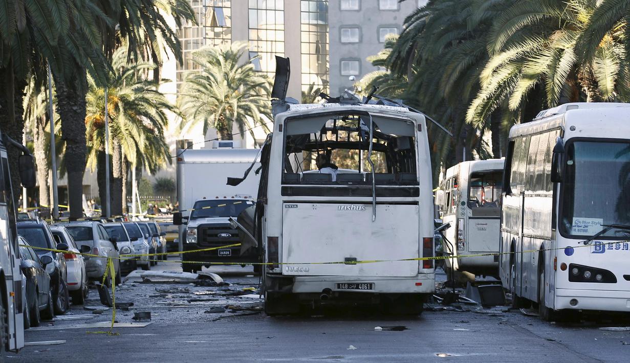Seorang petugas kepolisian saat memeriksa keadaan bis yang hancur pasca serangan bom di Tunisia, (25/11).  Peristiwa pemboman ini menewaskan sedikitnya 13 orang. (REUTERS/Zoubeir Souissi)
