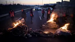 Anggota serikat pekerja memblokir jalan dalam sebuah aksi untuk menentang perombakan dana pensiun yang sangat tidak populer di Donges, Prancis Barat, Rabu (8/2/2023). Prancis bersiap menghadapi pemogokan baru dan demonstrasi massal menentang proposal Presiden Prancis untuk mereformasi pensiun Prancis, termasuk menaikkan usia pensiun dari 62 menjadi 64 tahun. (LOIC VENANCE/AFP)