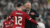 Manajer Liverpool, Arne Slot (kanan), memberi selamat kepada bek Liverpool asal Irlandia Utara nomor punggung 12, Conor Bradley (kiri), di lapangan setelah pertandingan sepak bola fase liga Liga Champions UEFA antara Liverpool dan Real Madrid di Anfield, Liverpool, Inggris barat laut, pada 4 November 2025. Liverpool menang 1-0. (Paul ELLIS / AFP)