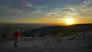 Seorang pejalan kaki memotret matahari terbit di atas Lembah di puncak South Mountain, Phoenix, Senin (17/7/2023). (AP Photo/Matt York)