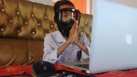 Salah satu peserta ujian semester tingkat SD sederajat di Ternate. Tampak sedang mengenakan topeng pelindung diri karena pandemi corona sesaat sebelum mengisi jawaban dari soal-soal yang diberikan pihak guru di sekolah melalui pesan WhatsApp. (Liputan6.com/Hairil Hiar)