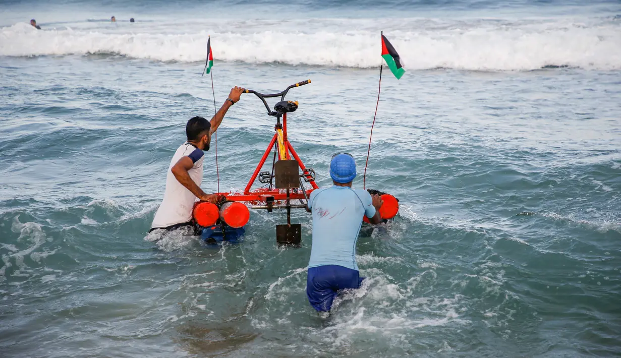 Nelayan Palestina membawa perahu kayuh yang dibuat khusus dari bahan daur ulang ke dalam air di sepanjang pantai di Beit Lahia, Jalur Gaza pada 29 September 2020. (Photo by MOHAMMED ABED / AFP)