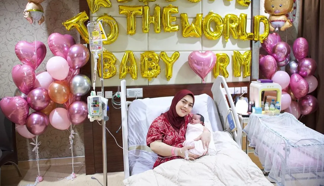 Aisyahrani, menggendong buah cintanya ketiga di sebuah rumah sakit. Tampak wajah bayi RM yang digendong sang ibu mengarah ke kamera. (Foto: Syh55)