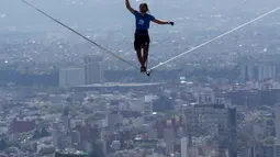 Alexander Schultz berjalan di atas tali sepanjang 217 meter yang menghubungkan dua gedung tertinggi Mexico City di Meksiko, 4 Desember 2016. Schultz butuh lima kali upaya menaklukkan tali yang dipasang pada ketinggian 246 meter tersebut (REUTERS/Stringer)