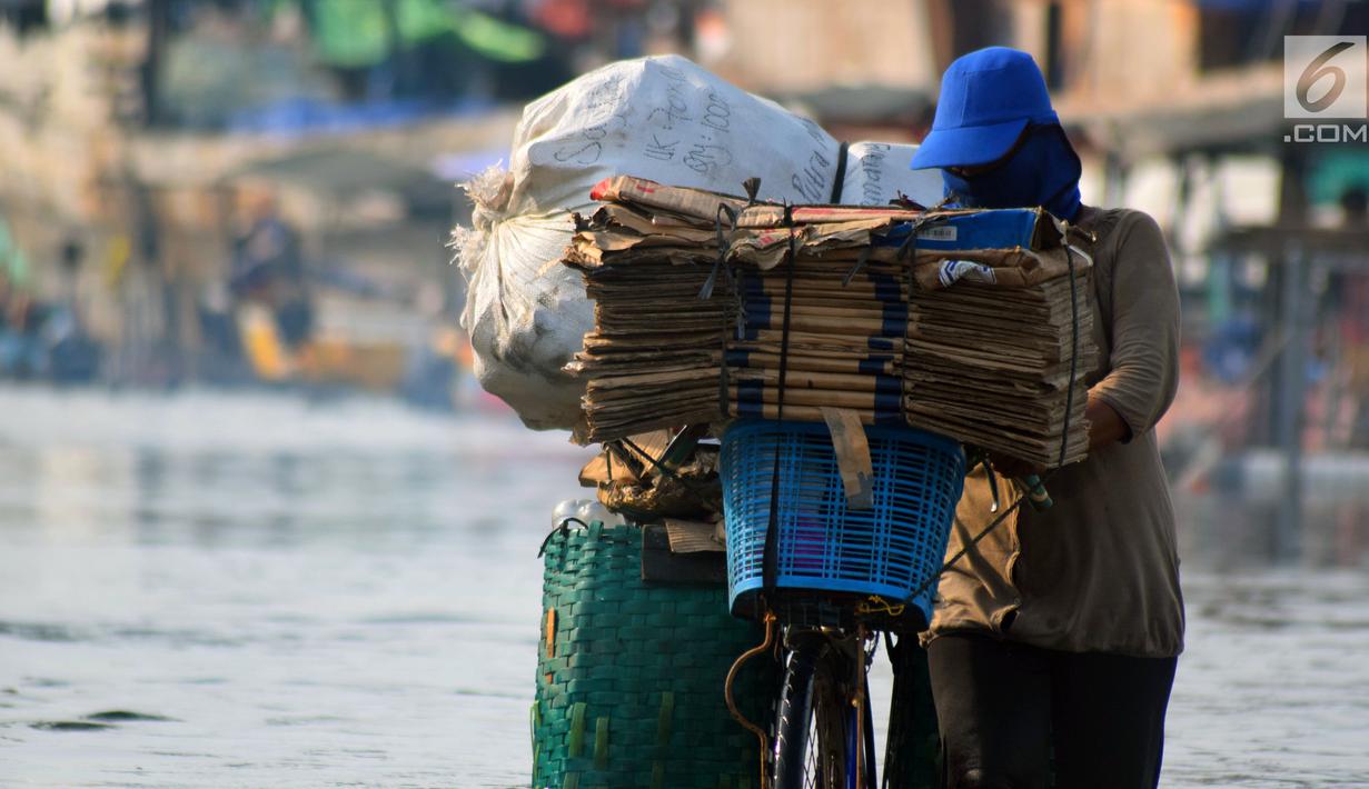 Seorang warga mendorong sepedanya melintasi banjir rob di jalan Yos Sudarso Semarang di kawasan Pelabuhan Tanjung Emas (24/4). Banjir akibat pasang air laut masih terjadi di sejumlah titik kota Semarang. (Liputan6.com/Gholib)