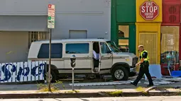 Petugas kepolisian berjalan dekat mobil van yang menabrak kerumunan orang di depan sebuah restoran di Los Angeles, Minggu (30/7). Van itu menabrak truk pickup sebelum menabrak pembatas jalan dan menghantam bagian luar resto. (AP Photo/Damian Dovarganes)