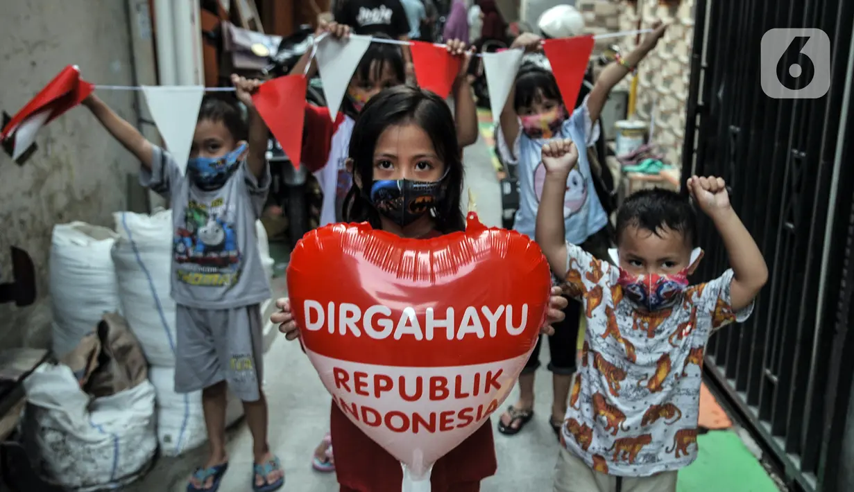 Anak-anak membawa atribut bernuansa HUT RI di Gang A, RT 10/11, Pademangan Timur, Jakarta, Rabu (5/8/2020). Dalam rangka menyambut HUT ke-75 RI, gang tersebut bersolek dengan mewarnai jalan hingga memasang bendera Merah Putih serta beragam atribut kemerdekaan. (merdeka.com/Iqbal S. Nugroho)