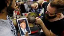 Tukang cukur rambut, Muhannad Khaled Omar membuat lukisan bergambar Donald Trump dikepala pelanggannya di Burj al-Barajneh, Lebanon (14/7). Omar adalah penata rambut yang terkenal membuat lukisan di kepala pelanggannya.  (AP Photo / Bilal Hussein)