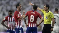 Wasit memberikan peringatan kepada bek Atletico Madrid, Diego Godin, saat melawan Real Madrid pada laga La liga di Stadion Santiago Bernabeu, Madrid, Sabtu (29/9/2018). Kedua klub bermain imbang 0-0. (AFP/Oscar Del Pozo)